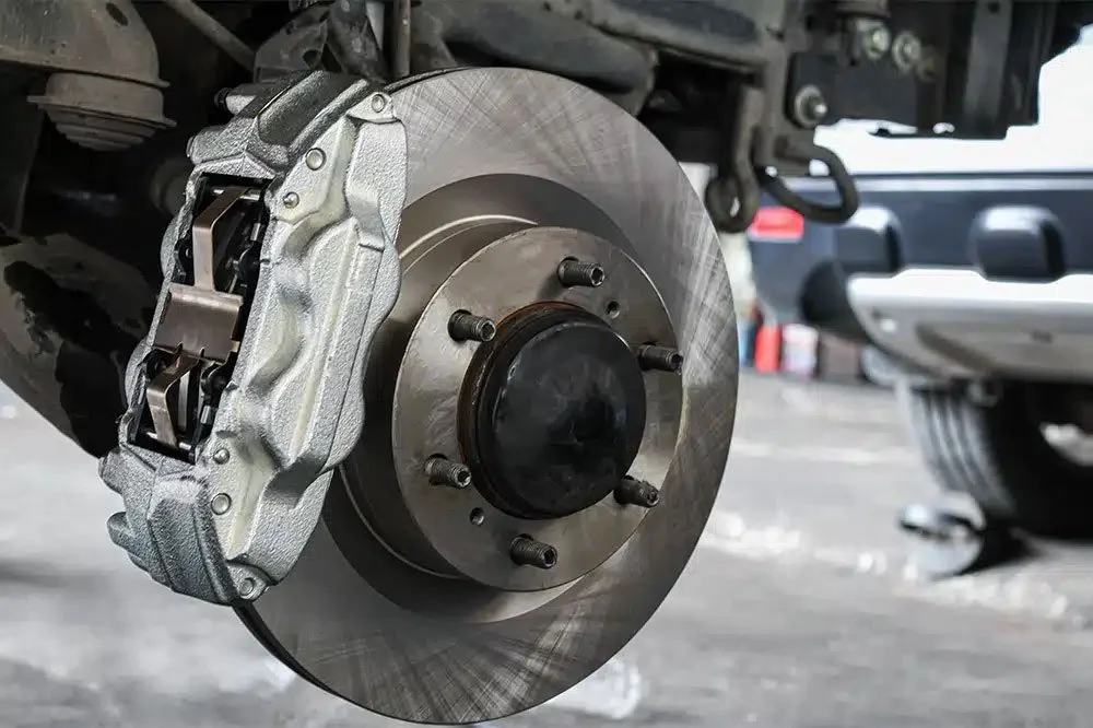 Close-up of a freshly installed brake rotor and caliper on a vehicle